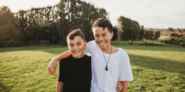 Two Māori kids standing in field